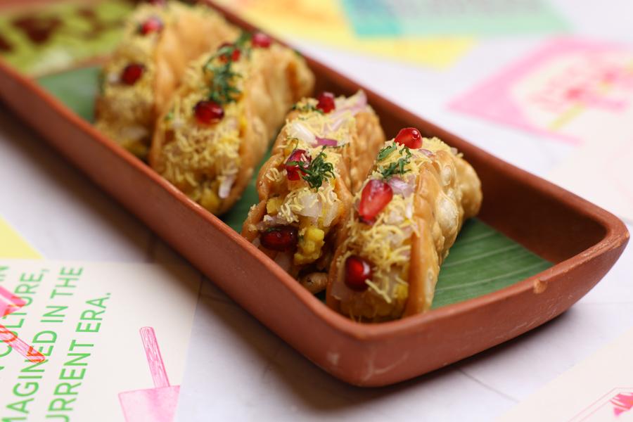 Dal pakwan tacos topped with sev and pomegranate in a terracotta dish